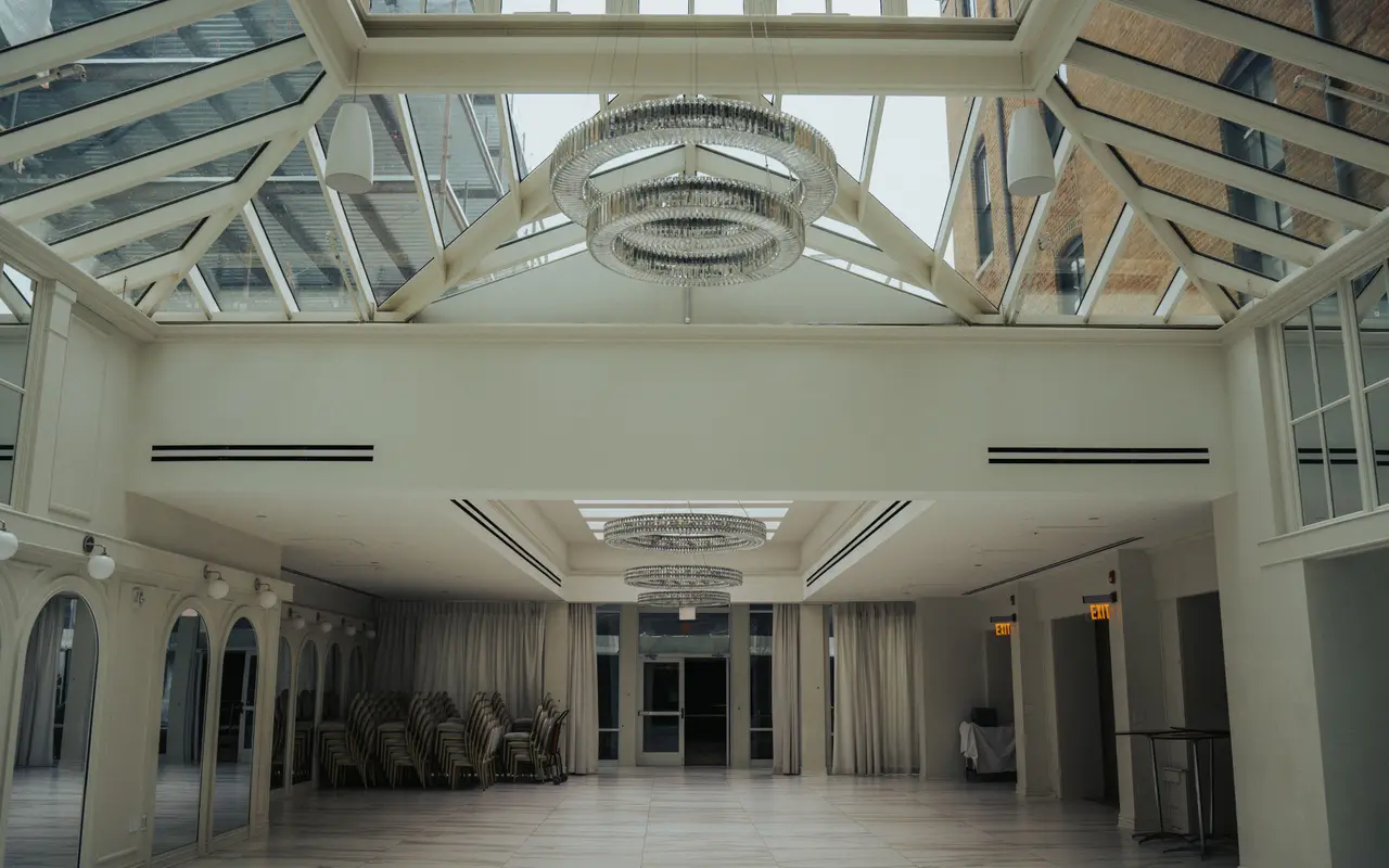 An empty event hall with a glass roof and chandeliers, floor clear and ready to be set