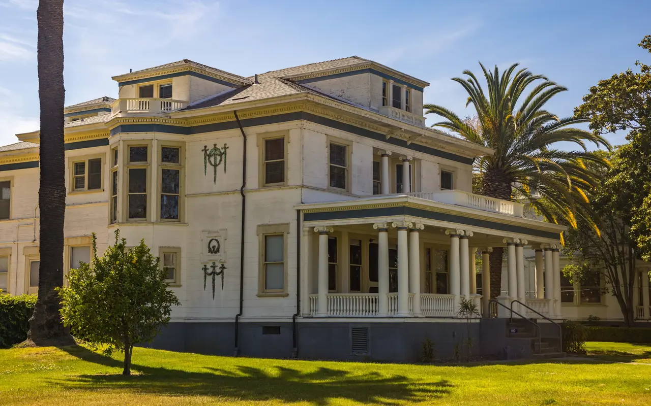 A white historic mansion with a columned porch, photographed across its front lawn