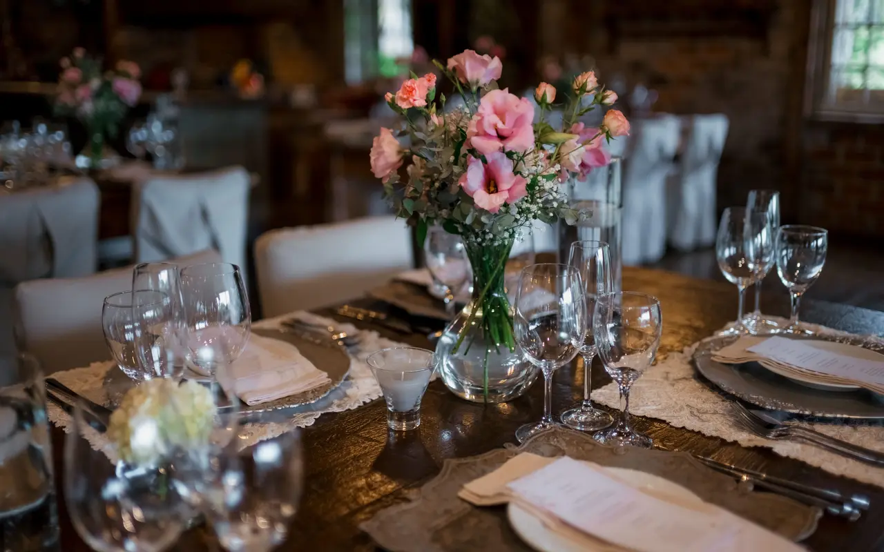 A close view of a dressed venue table: floral centerpiece, glassware, linen and place settings